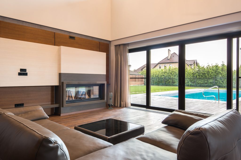 Spacious modern living room with glass doors opening to a poolside area.